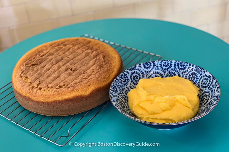 Sponge cake cooling on rack next to the pastry cream