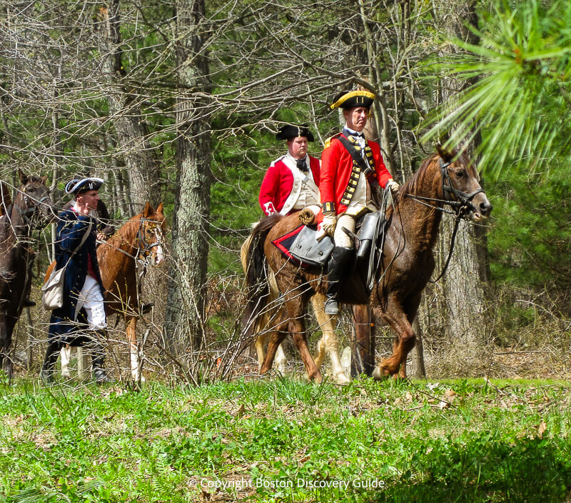 Reenactors portraying British troops march toward a 1775 battlesite at Minute Man National Historic Park