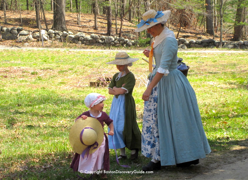 Reenactor portraying a Colonial woman with two young daughters during Patriots Day celebration Reenactor portraying a Colonial woman with two young daughters during Patriots Day celebration