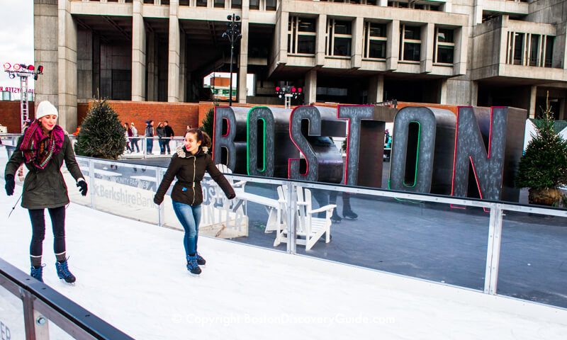 Winter Market ice skaters in front of the neon Boston sign Winter Market ice skaters in front of the neon Boston sign