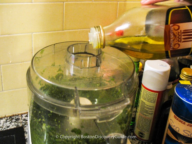 Adding the olive oil for the pesto to the food processor