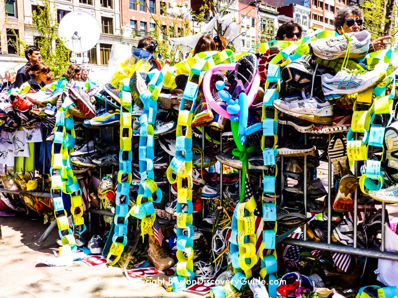 Dozens, maybe hundreds of pairs of running shoes along this barricade near Copley Square