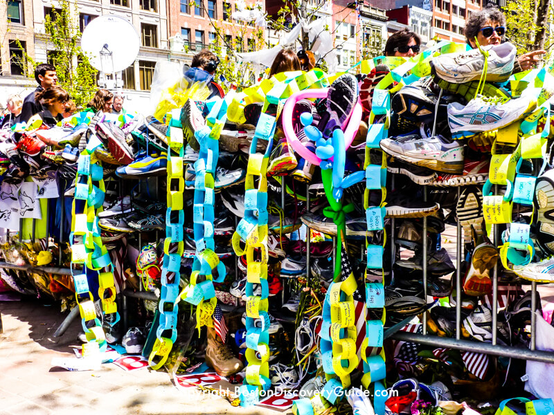 Dozens, maybe hundreds of pairs of running shoes along this barricade near Copley Square