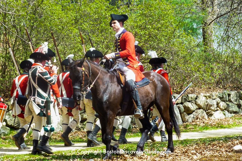 Reenactors portraying British troops march toward a 1775 battlesite at Minute Man National Historic Park